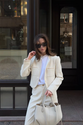 a lady in a white top, a white tweed coat, and a pair of white pants
